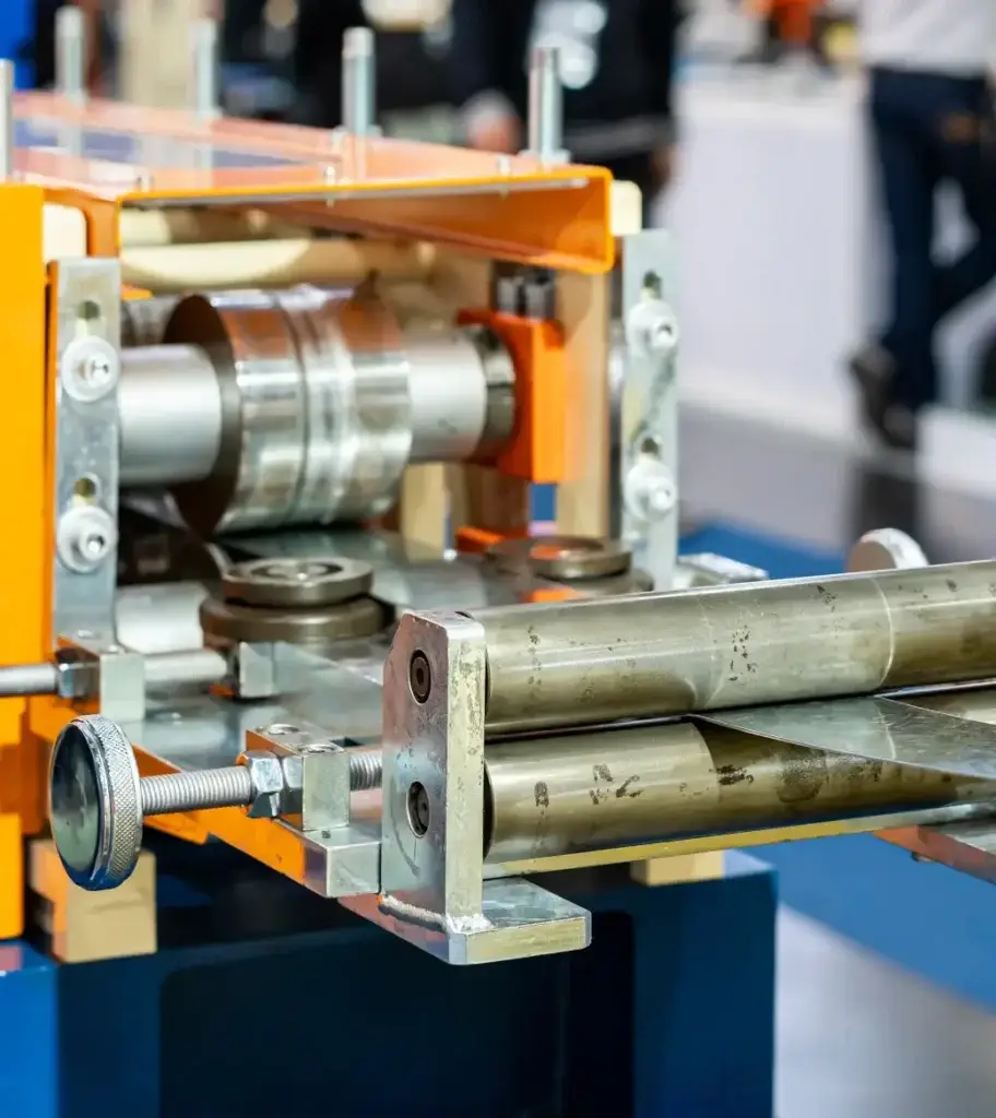Industrial metal forming machine with orange frame and steel rollers for sheet metal processing.