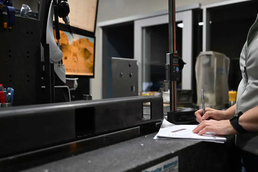 Quality Technician verifying part measurements meet engineering print.